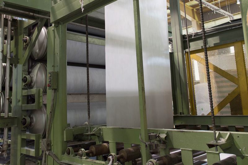 Línea de producción de tela no tejida: el velo blanco avanza a lo ancho entre los rodillos y tambores de la máquina