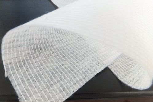 Detalle de tela stitch bond: las hileras paralelas de hilo de costura recorren el velo y dibujan sobre él una malla regular