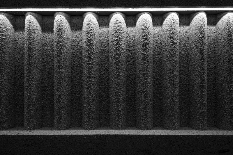 Macro de un medio filtrante plisado: los pliegues verticales del material retienen polvo en la superficie, bajo luz lateral