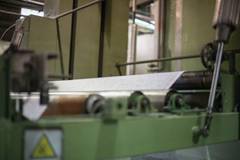 Velo de tela no tejida en proceso pasando por los rodillos de una máquina de la planta de Notesa